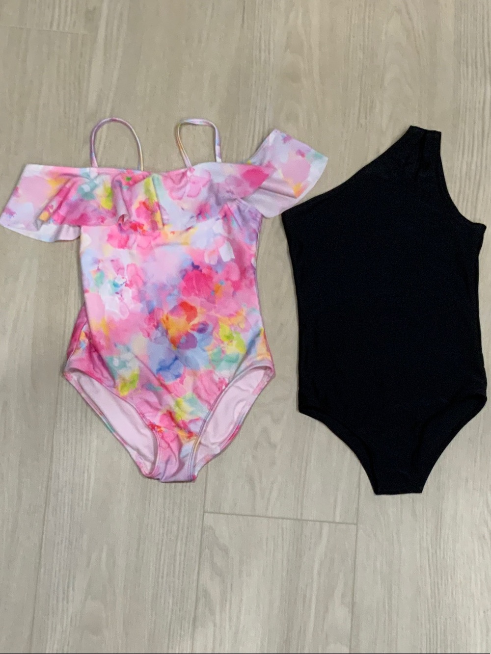 Girls Floral Pink Ruffle One-Piece Swimsuit with A Black One-piece Swimsuit.
